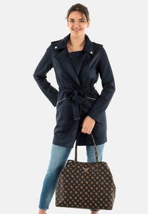 Manteau trench bleu marine avec une ceinture à nouer, deux poches zippées et des épaulettes ; associé à un sac à main marron à motifs.