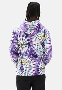 Sudadera con capucha de teñido anudado en múltiples colores, que presenta patrones de espiral en púrpura, azul y amarillo, con cordones en la capucha y dobladillo negro acanalado.