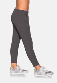 Szare legginsy o dopasowanym kroju, miękkiej fakturze i elastycznej talii, zestawione ze srebrnymi trampkami zdobionymi brokatowymi akcentami.