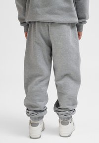 Grijze joggingbroek met elastische boorden en een losse fit, gemaakt van een zachte stof, gecombineerd met lichte sport sneakers.