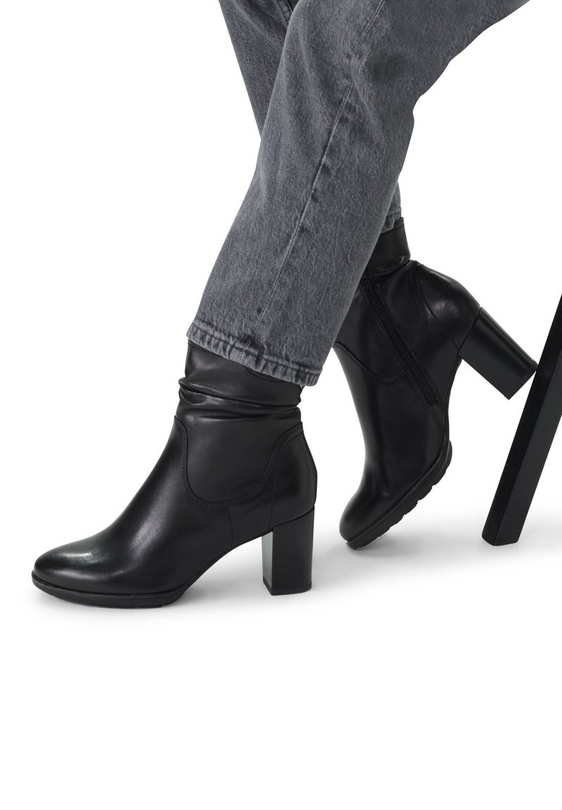 Bottines en cuir noir avec une finition lisse, un bout arrondi et un talon carré. Présentent un design froncé au niveau de la cheville et une fermeture éclair latérale.