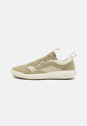 Sneaker featuring a mix of light green suede and beige fabric, a textured white sole, rounded toe, and lace-up design with back pull tab.