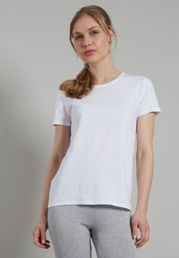 White cotton t-shirt with short sleeves, round neckline, and a relaxed fit. Smooth texture, minimal design without patterns or accents.