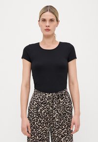 Schwarzes kurzärmliges T-Shirt mit Rundhalsausschnitt, kombiniert mit lässigen Hosen im Leopardenmuster, die einen verstellbaren Gürtel in der Taille haben.