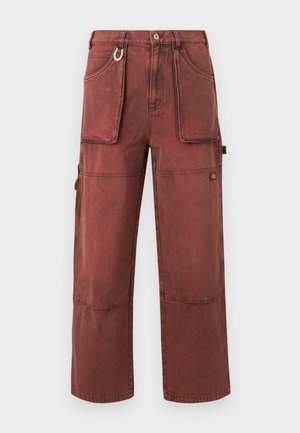 Παντελόνι cargo σε σκουριά κόκκινο με ίσια γραμμή, μεγάλες μπροστινές τσέπες, ραφές στα γόνατα, θηλιές για ζώνη, μεταλλικό κρίκο κλειδιών και κούμπωμα με κουμπί.