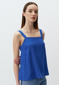 Koninklijk blauwe camisole met brede bandjes, vierkante halslijn en vloeiende silhouet. Gemaakt van gladde stof, lichtjes textuur, zonder versieringen.