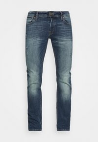 Jeans de denim azul escuro com corte slim, apresentando desbotamento ligeiro e patches desgastados. Design clássico de cinco bolsos com fecho de zip e botão.