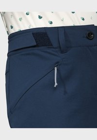 Marineblaue Hose aus gewebtem Stoff, mit seitlicher Reißverschlusstasche, verstellbarem Bund mit Klettverschluss und Knopfverschluss.