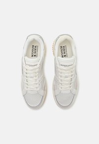 Hvide sneakers med en blanding af glatte og perforerede materialer, snørebåndsdesign, gummisål og diskret branding på tungen.