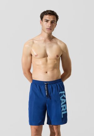 Blaue Herrenschwimmshorts mit Kordelzugbund und großem "KARL"-Logo in Hellblau auf der linken Seite. Glattes, leichtes Gewebe.