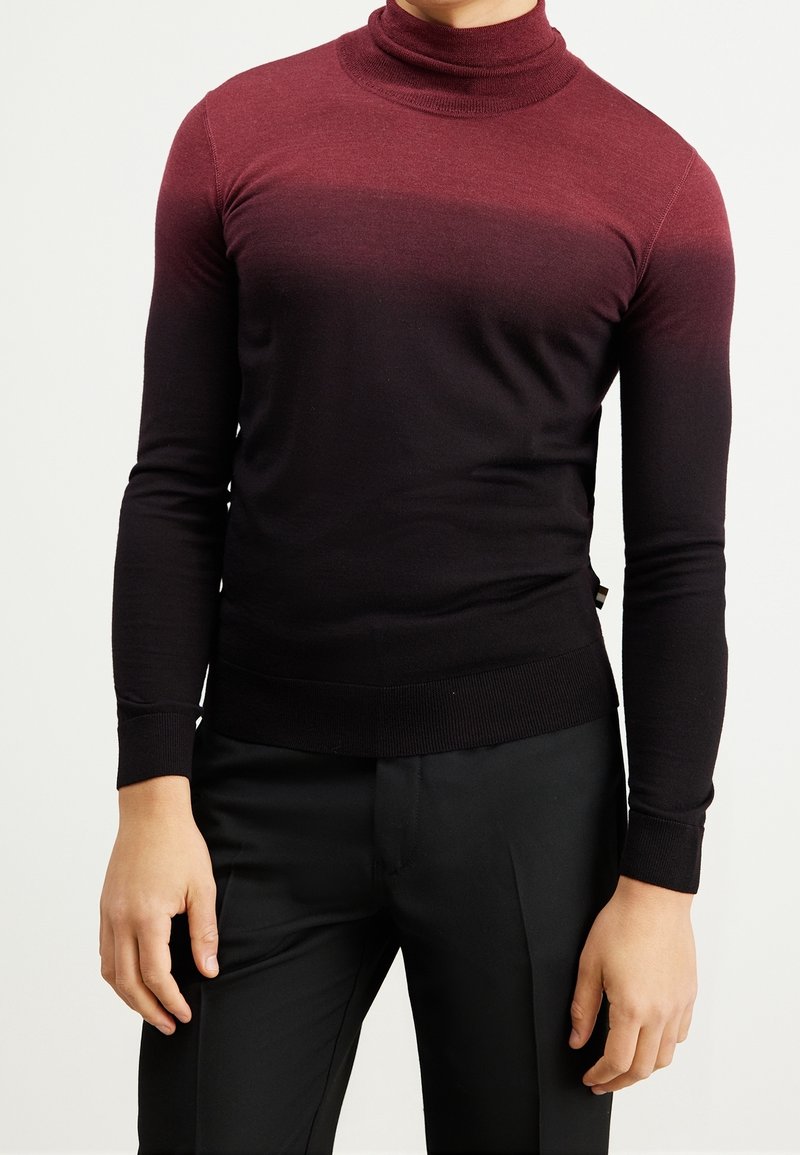 Pull à col roulé avec dégradé du bordeaux au noir, confectionné en tissu doux. Coupe ajustée avec manches longues et poignets ainsi qu'ourlet côtelés.