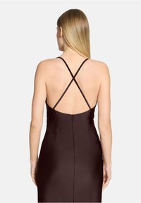 Robe en satin marron avec un dos nu et des bretelles croisées, fermeture éclair. Le tissu a une texture lisse et brillante.