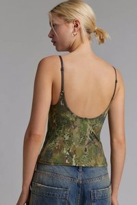 Top in stampa mimetica nelle tonalità di verde, con schiena bassa, spalline sottili e design aderente. Indossato con jeans in denim a vita alta.