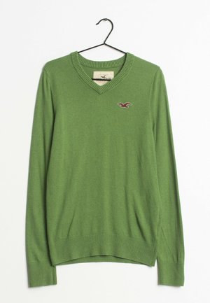 Pull vert à col en V manches longues sur cintre noir avec petit logo oiseau brodé sur la poitrine gauche.