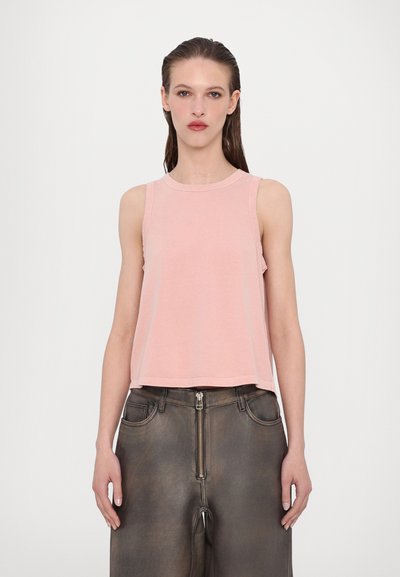 Lichtroze, mouwloze, cropped top met een ronde halslijn en stikdetails, gecombineerd met hoog-waisted, donkere, gestructureerde broek met een rits aan de voorkant.