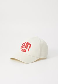 Un capac de baseball bej cu o vizieră curbă, având textul brodat roșu "GANT 49" pe partea din față. Materialul are o textură netedă.