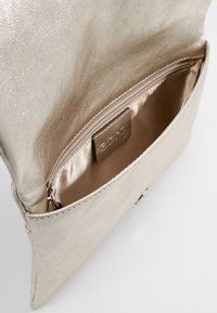 Pochette en cuir beige avec poche zippée et intérieur en tissu, montrée partiellement ouverte sur un fond blanc.