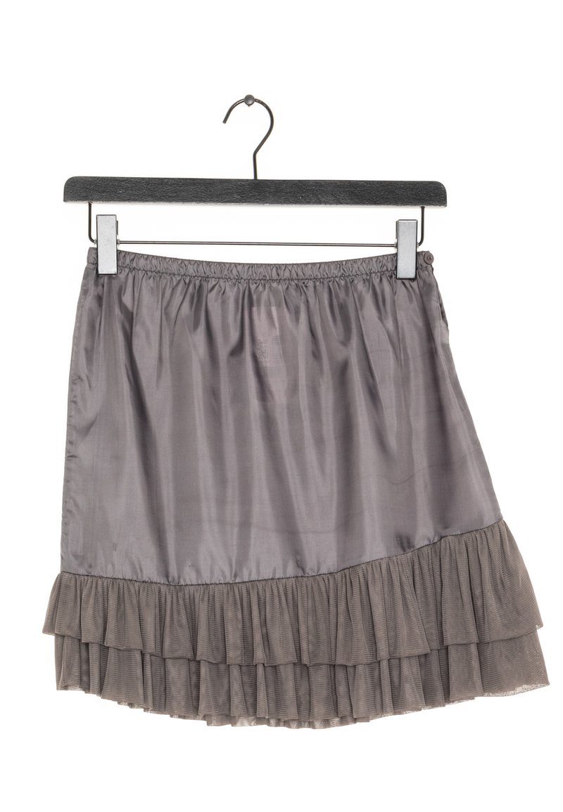 Šedá vícevrstvá sukně vyrobená z lehkého materiálu, s volánkovým lemem a elastickým pasem, zavěšená na černém dřevěném ramínku.