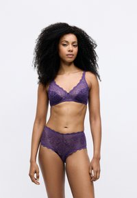 Vijolična čipkasta bralette z valovitim robom, v kombinaciji z ujemajočimi se čipkastimi hlačkami hipster, ki vključujejo zapletene vzorce in mehko teksturo.