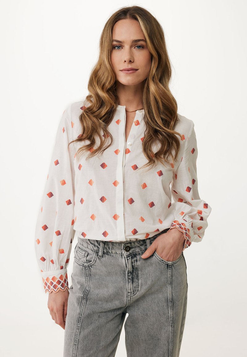 Camicia bianca con motivi a rombi colorati, con bottoni frontali, in tessuto leggero, maniche lunghe con polsini fantasiosi, abbinata a jeans grigi a vita alta.