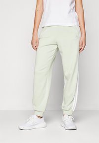 adidas Sportswear ESSENTIALS 3-STRIPES LOOSE-FIT - Tepláky - linen green