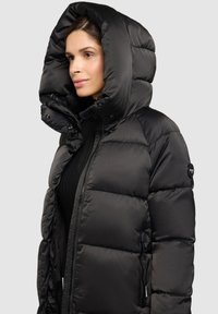 Must tikitud talvejope kõrge krae ja üle suurendatud kapuutsiga. Õmmeldud muster, hõbedased detailid ja voolujooneline lõige. Varustatud tõmblukuga sulgemisega.