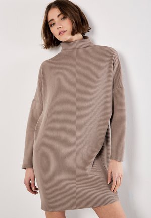 Rippstrick-Turtleneck-Kleid in Hellbraun, mit lockerer Passform, langen Ärmeln und seitlichen Schlitzen für Bewegungsfreiheit. Weiche Textur.