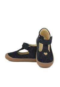 Chaussures Mary Jane en suède pailleté bleu marine, avec une sangle à fermeture velcro, un bout en forme d'amande et une découpe en forme de cœur sur chaque côté de la chaussure.