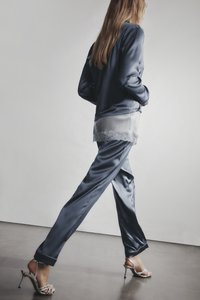 Námořnické saténové pyžamo se dlouhými rukávy, krajkovým lemem na spodní části. Kombinováno se stříbrnými sandály na vysokém podpatku se šněrováním. Hladká, lesklá textura.