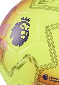 Pallone da calcio giallo brillante con accenti neri, logo di un leone, superficie texturizzata e motivi geometrici a linee. Taglia 5, qualità FIFA.