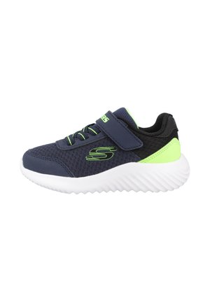 Zapatilla atlética de malla azul marino con acentos verdes, suela blanca ondulada, correa ajustable de Velcro y detalles de textil negro.