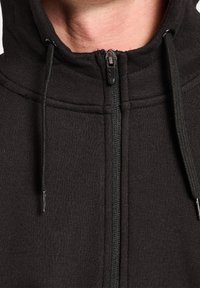 Svart zip-up hoodie med hög krage, med dragsko, mjuk textur och en centrerad dragkedja med metalliska accenter.