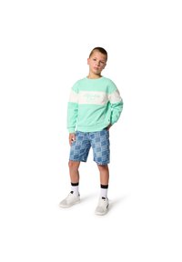 Ανοιχτό πράσινο φούτερ με λευκή ρίγα και λογότυπο, σε συνδυασμό με μπλε σορτς που έχουν επαναλαμβανόμενο μοτίβο λογότυπου. Λευκά αθλητικά παπούτσια και μαύρες κάλτσες.