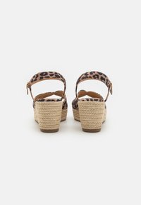 Sandales à talons compensés en imprimé léopard avec un talon en jute, bride de cheville ajustable et design à dos ouvert. Matériau doux et finition texturée.