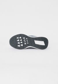 Czarna gumowa podeszwa z trójkątnym wzorem bieżnika, biała środkowa część i granatowa cholewka. Posiada prostokątny logo Lacoste z boku.