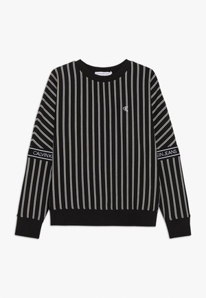Felpa nera a righe con linee verticali bianche, polsini a costine e scollo rotondo. Presenta un piccolo logo Calvin Klein sul petto.