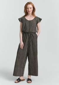 Gestreepte jumpsuit van zwart en wit stof, met korte fladdermouwen, een verstelbare taille, een wijde broekspijpenontwerp en zijzakken.