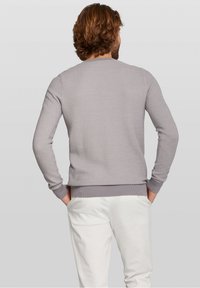 Jersey tejido de color gris claro con cuello redondo y puños acanalados, que presenta una textura sutil y una forma ligeramente ajustada, combinado con pantalones blancos.