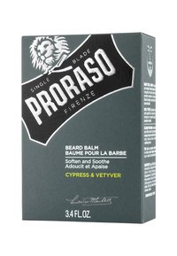 Emballage de baume à barbe en noir mat et gris. Présente un logo de lion, le nom du produit en blanc et un texte vert pour le parfum. Taille de 100 ml.