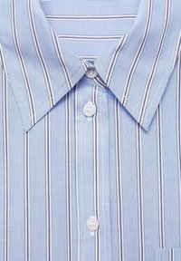 Chemise rayée bleu clair avec de fines rayures verticales blanches et bleu foncé, un col pointu et des boutons blancs sur la patte de boutonnage.