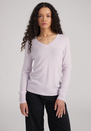 V-Ausschnitt, helllila Pullover aus weichem Material mit gerippten Bündchen und Saum, kombiniert mit schwarzen Hosen für den Kontrast.