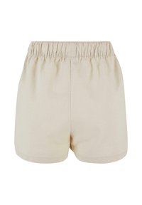 Short beige à taille élastique avec un tissu lisse et un design simple, vu de dos sur fond blanc.