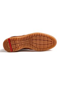 Semelle de chaussure avec un design en caoutchouc texturé de couleur sable, avec des rainures de flexion et un accent rouge. Nom de la marque "LLOYD" embossé.