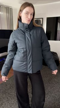 Σκούρο μπλε μονωμένο μπουφάν τύπου puffer με ψηλό γιακά, εμπρόσθιο φερμουάρ και πλαϊνές τσέπες. Το ύφασμα φαίνεται λείο και ελαφρώς γυαλιστερό.