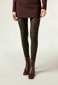 Collant neri a motivo con un design a diamante e dettagli dorati. Abbinati a stivaletti bordeaux con chiusura con zip e punta quadrata.
