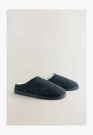 Tmavomodré tkané papuče s textúrovaným vonkajším materiálom, mäkkou bielou podšívkou a čiernou gumovou podrážkou. Dizajn na obúvanie bez zapínania.