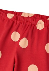 Pantalones cortos rojos con cintura elástica y grandes lunares beige. La tela tiene una textura suave y un diseño casual, adecuado para la comodidad y el ocio.