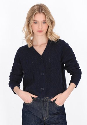 Navy blue cropped cardigan made of textured knit, featuring a deep V-neck, long sleeves, and heart-shaped buttons along the front.