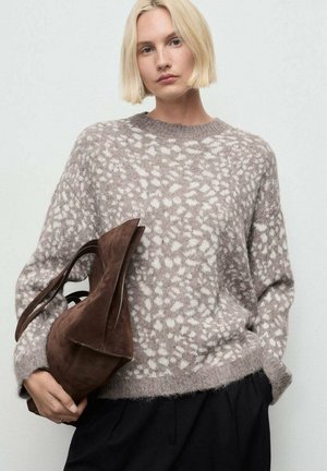 Pull gris clair avec des motifs abstraits blancs, col rond et coupe loose. Sac en suède marron de forme courbée avec des poignées courtes.