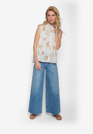 Lichtgewicht mouwloze blouse met een schelpenprint, gecombineerd met wijd uitlopende blauwe denim jeans. De gestructureerde stof heeft subtiele kleuren en patronen.